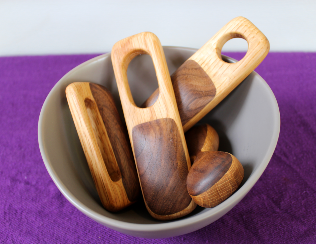 baby rattles made from scraps of walnut and oak Four rattles of different shapes nestle in a mixing bowl on a purple background. Each one is made from contrasting oak and walnut. Custom made by in the Shawangunk mountains by local artisan.